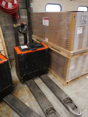 a fork lifter in a warehouse next to a stack of boxes