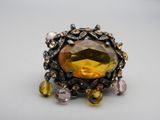 un gros plan d'une bague ornée d'une pierre jaune entourée de cristaux