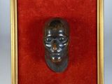 une image représentant une tête d'homme en bronze dans un cadre doré