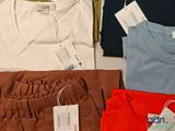 a lot of t - shirts on a table with tags on them