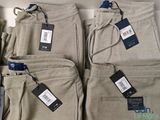 several men ' s pants are lined up on a shelf in a store