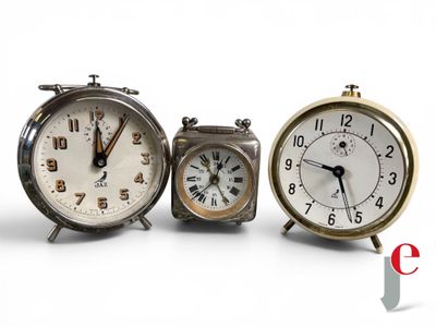 three clocks sitting next to each other on a white surface