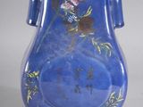 a blue vase with a bird and flowers on it