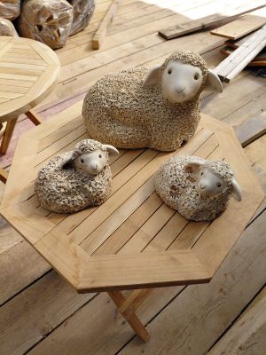 trois moutons assis sur une table en bois posée sur un plancher en bois