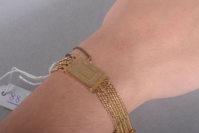 la main d'une femme portant un bracelet en or et une médaille