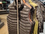 many jackets hanging on a rack in a clothing store