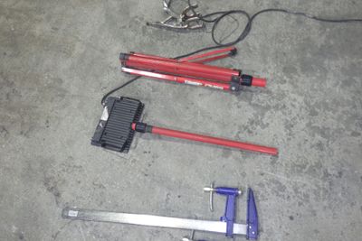 des outils éparpillés sur le sol d'un garage, notamment un marteau, une clé et une paire de ciseaux