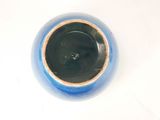 a blue vase with a brown rim on a white table