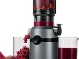 un extracteur de jus posé à côté d'un verre de jus