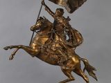 statue représentant un homme à cheval tenant un drapeau, posée sur un socle en bois