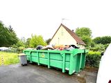 a green dumpster sitting in the middle of the road