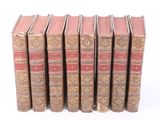 several old books are lined up in a row on a white surface