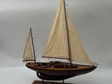 une petite maquette de voilier posée sur un socle en bois