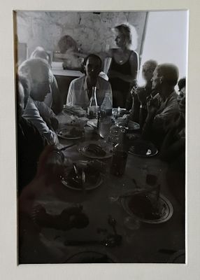 une photo en noir et blanc montrant un groupe de personnes assises à une table