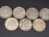 six different british coins sitting on top of each other on a black surface