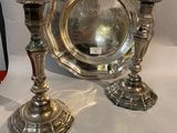 two silver candlesticks and a silver plate on a white background