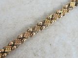 a close up of a gold bracelet on a marble surface