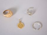 three gold rings and a silver ring on a white surface