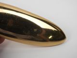 someone is holding a gold object in their hand on a white surface