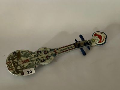 une cuillère en forme de guitare posée sur une surface blanche