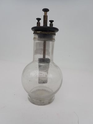 un bocal en verre muni d'une poignée en métal posé sur une surface blanche