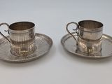 deux tasses et soucoupes en métal argenté, posées sur une soucoupe