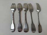 four forks are lined up on a white surface with silverware on them