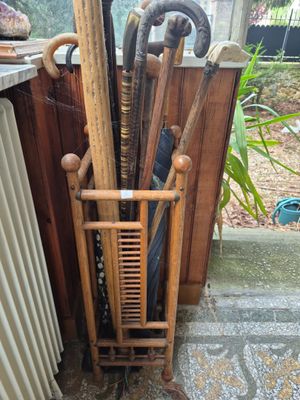 un porte-parapluies en bois sur lequel sont posés des parapluies et d'autres objets