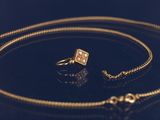 une image représentant un collier et une bague en or sur un fond noir