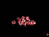 some pink diamonds are on a black surface with a black background