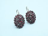 silver earrings with garnets on them on a blue background