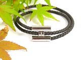a black leather bracelet that has two silver beads on it