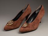 une paire de chaussures en daim marron avec une boucle dorée au talon
