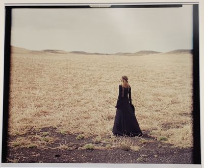 photo d'une femme vêtue d'une longue robe noire, debout dans un champ