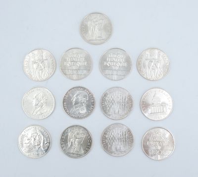 Plusieurs pièces de monnaie différentes sont disposées en triangle sur une surface blanche.
