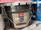 a bucket of paint sitting on the floor next to a bucket of paint