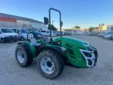 un tracteur vert garé sur un parking à côté d'un bâtiment