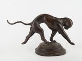 bronze statue of a dog running on a pedestal