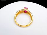 a gold ring with a pink stone on top of a white plate