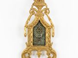 an image of a gold clock with a green face on a white wall