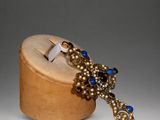 an image of a wooden box with a blue and gold broochet