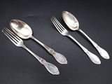 three silver spoons and two forks on a black surface