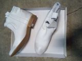 une paire de chaussures blanches dans une boîte posée par terre