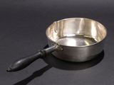 a small metal bowl with a wooden handle on a black surface