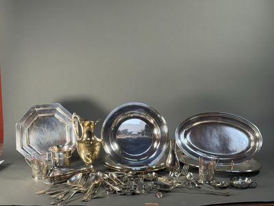 three silver dishes on a table next to a candle
