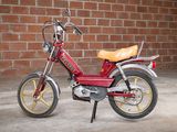 a small red motorcycle parked in front of a brick wall