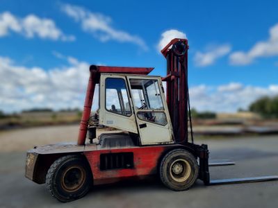 a red and white forklift truck parked in a parking lot