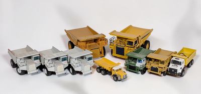 plusieurs camions jouets sont alignés sur une surface blanche