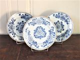 trois assiettes bleues et blanches posées sur une table en bois