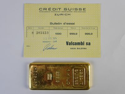 un lingot d'or et une carte de crédit posés l'un à côté de l'autre sur une table